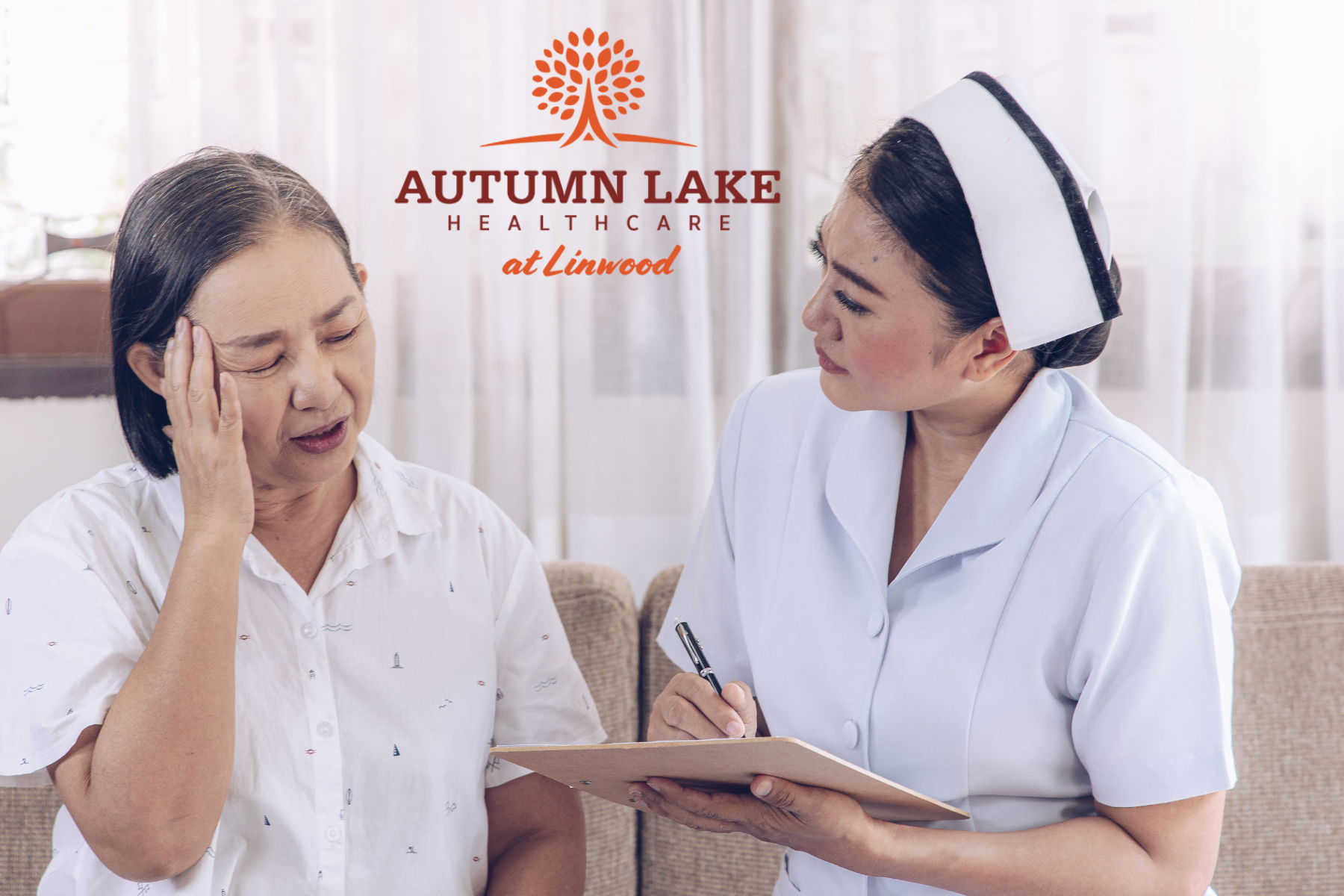 A nurse in a white uniform listens attentively and takes notes while a female resident describes her symptoms at Autumn Lake Healthcare at Linwood.